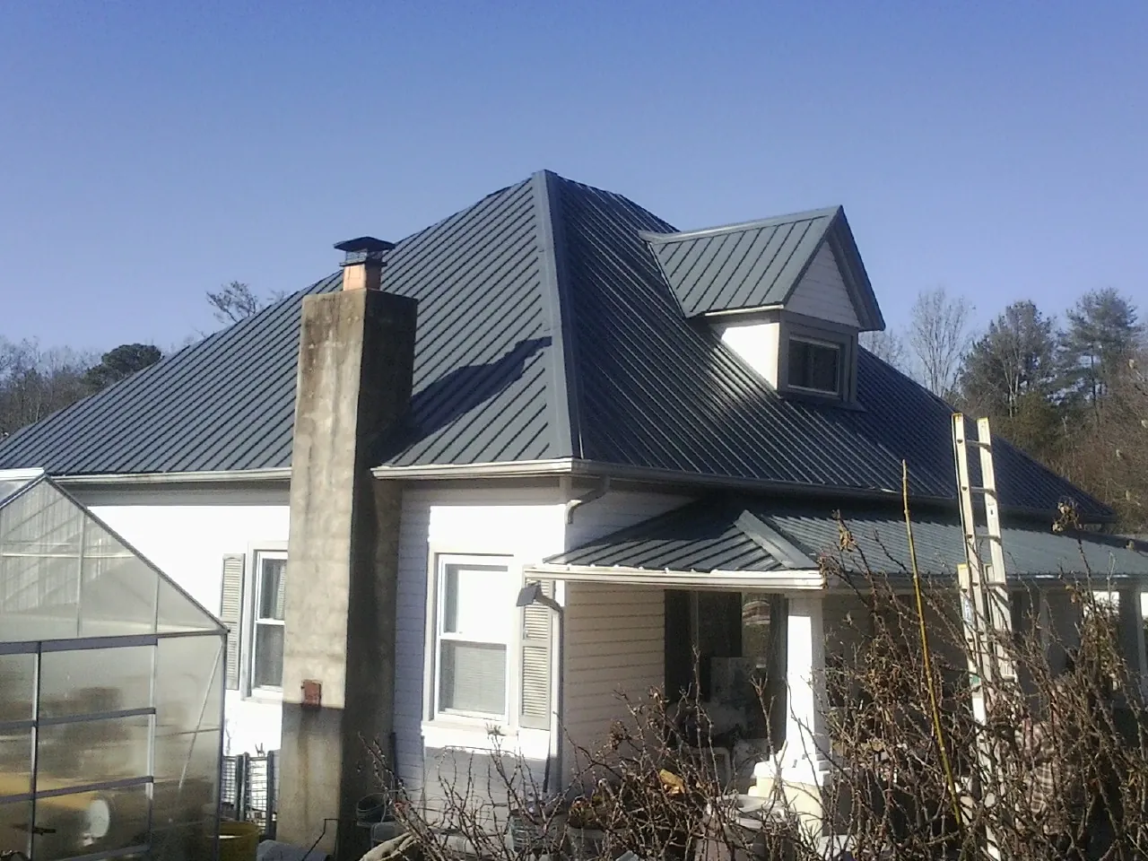 Dark blue standing seam metal roof on a white farmhouse with dormer — Slate & Tile Roof Repair by Roofing Brothers in La Salle