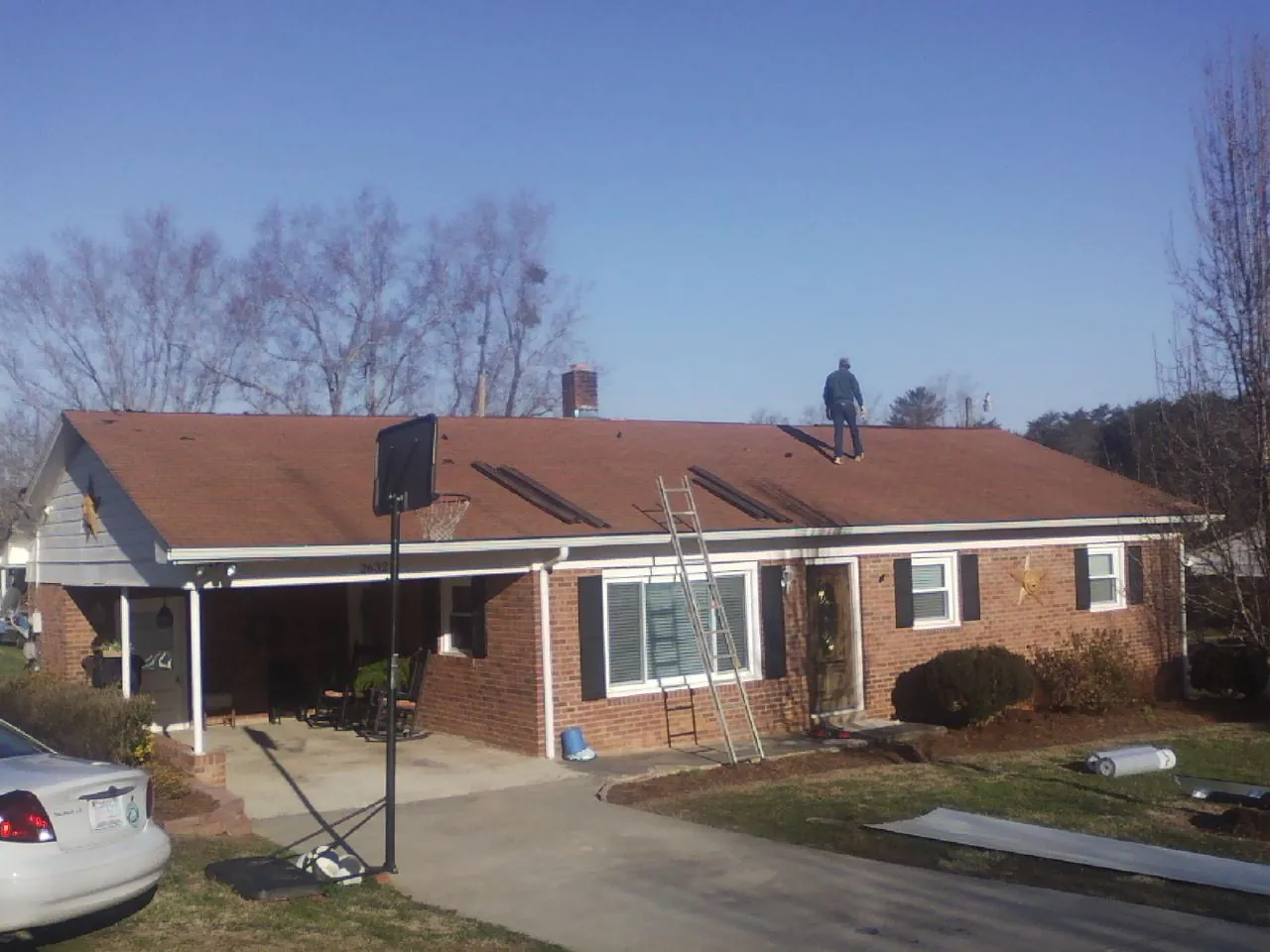 Roofer stripping a shingle roof on a brick ranch before metal panels in La Salle