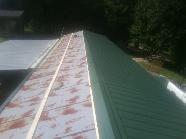 Old rusted panels beside newly installed green metal roofing — Wind Damage Roof Repair by Roofing Brothers in La Salle